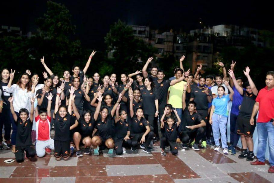 GO Speed Academy family - athletes and team members in uniforms celebrating together with raised hands, showcasing team spirit and unity