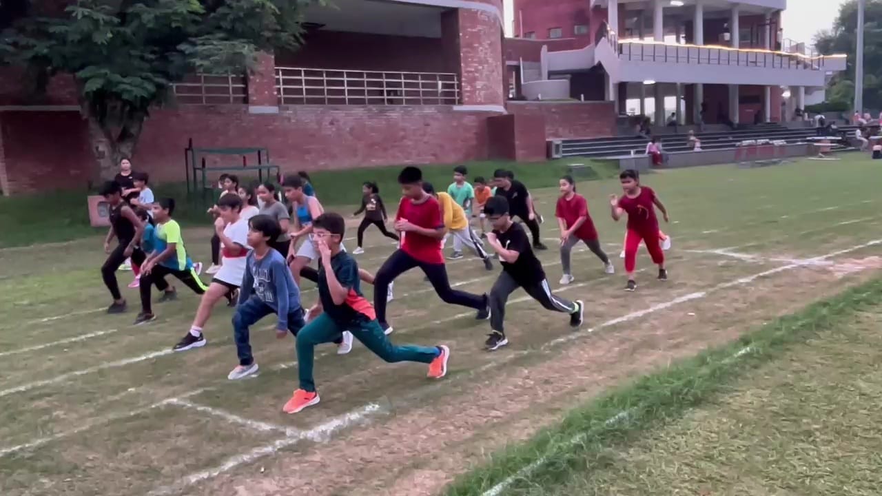 Athletic young man in black sportswear sprinting on outdoor track with intense focus and proper running form