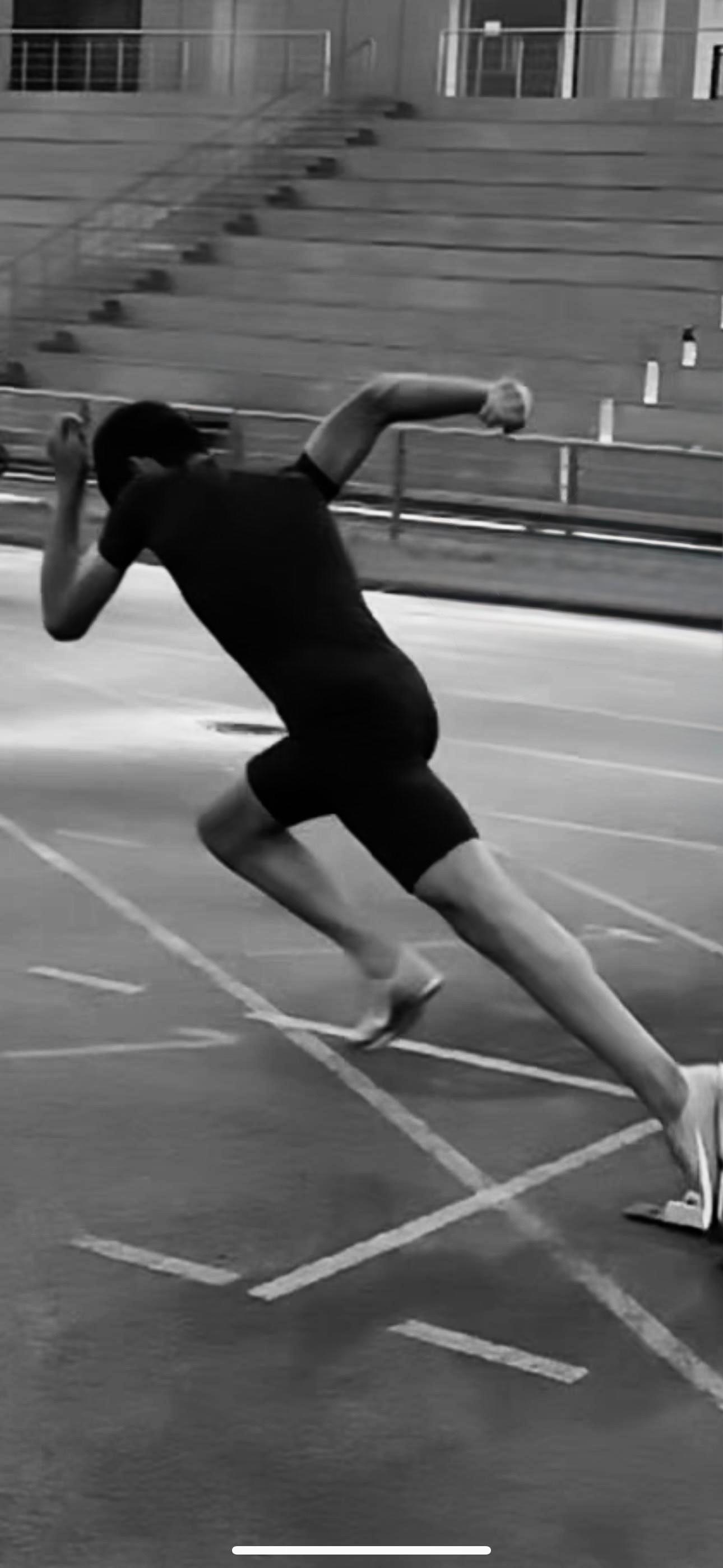 Black and white photo of athlete in starting position on track demonstrating explosive power and focus